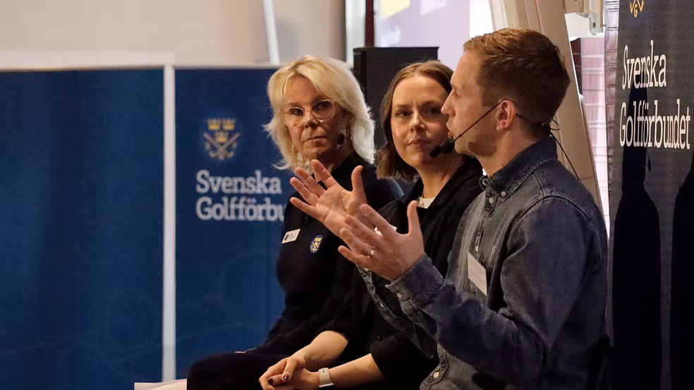 Två kvinnor och en man i en panel på en scen. I bakgrunden syns Svenska Golfförbundets logotyp.
