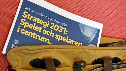 Brun väska med en blå broschyr om strategi 2031 för spelet och spelaren i centrum