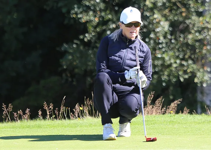 En golfspelare sitter ner och läser puttlinjen på green