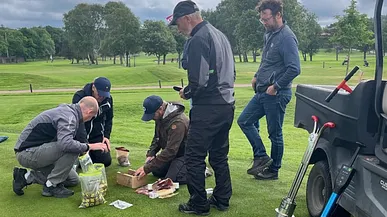 Fem män undersöker konditionen på en golfgreen med olika mätinstrument.
