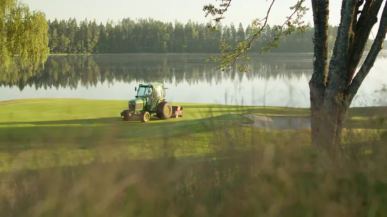 Greenklippare på en green vid vattnet.
